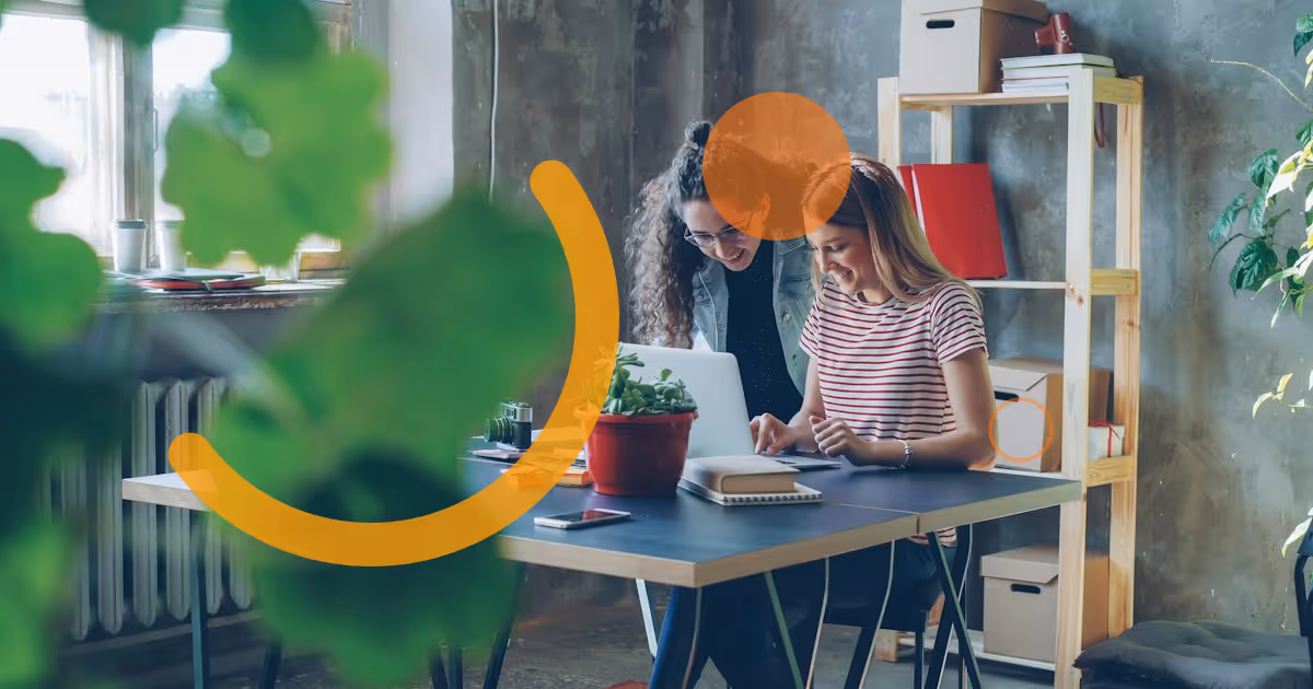 Deux collègues qui travaillent ensemble à un bureau, dans un espace de travail moderne, devant un ordinateur portable.