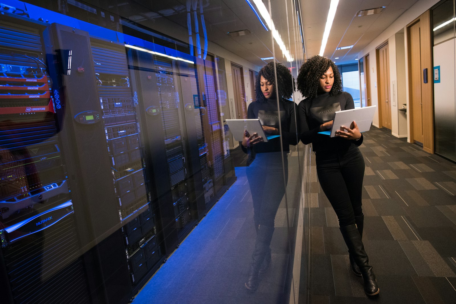 Une professionnelle de la tech consultant des données sur une tablette dans une salle serveur, illustrant la maîtrise technologique que la génération Z apporte à l'entreprise.