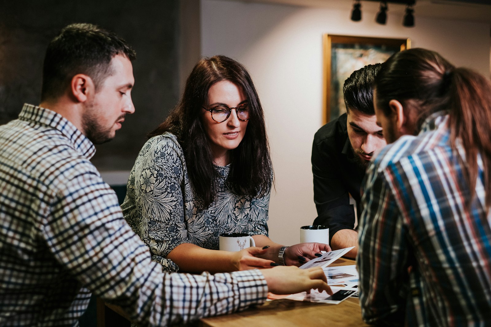 Colleagues gathered around a table with coffee, reviewing notes together, representing teams reconnecting and realigning in September.