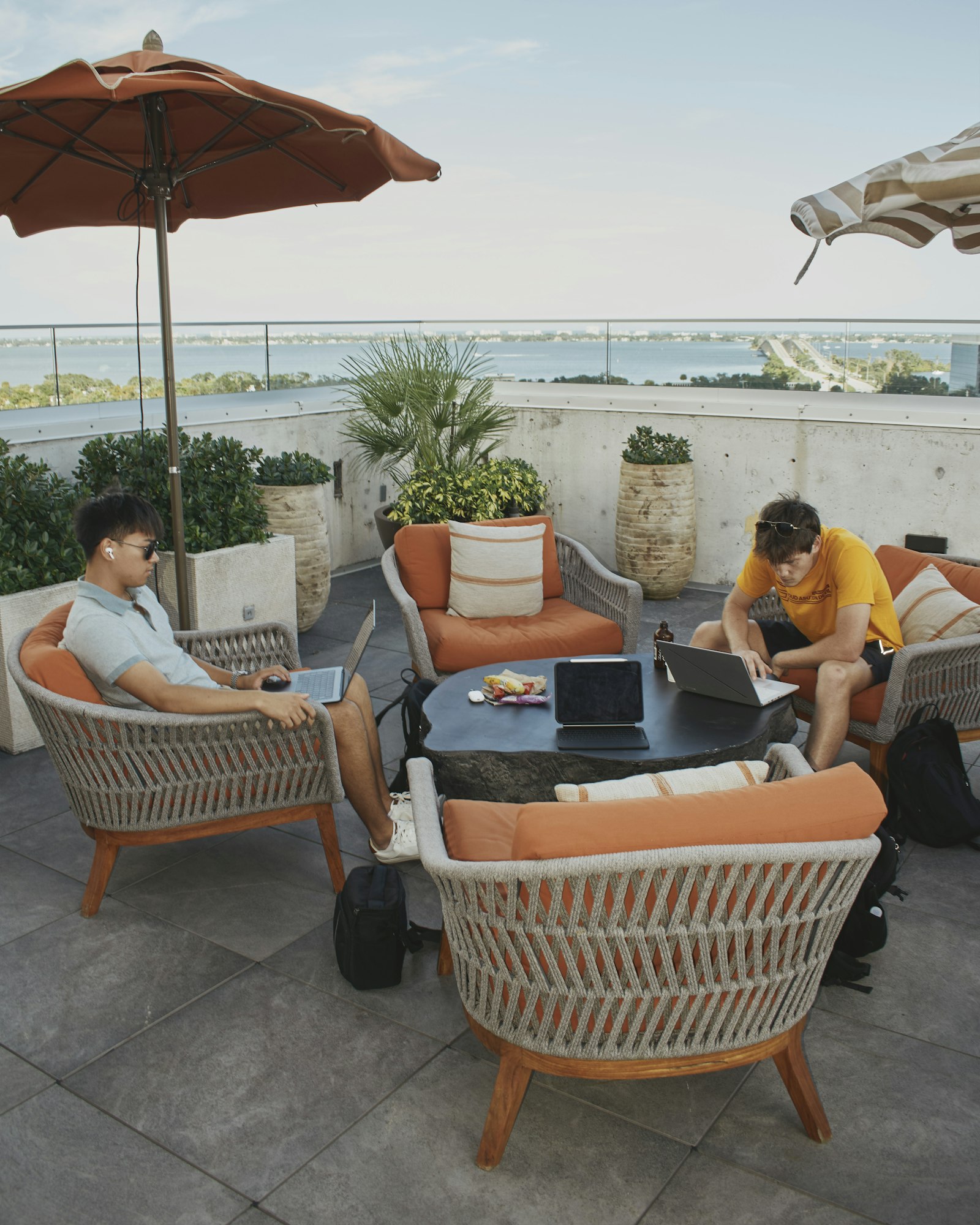 Deux collègues travaillant ensemble sur une terrasse ensoleillée, illustrant le travail flexible et la connexion d'équipe en été.